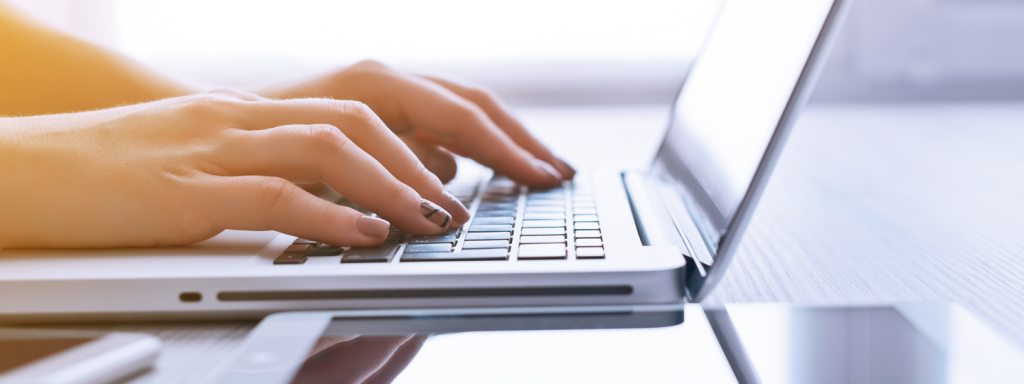 A close up of two hands typing on a laptop